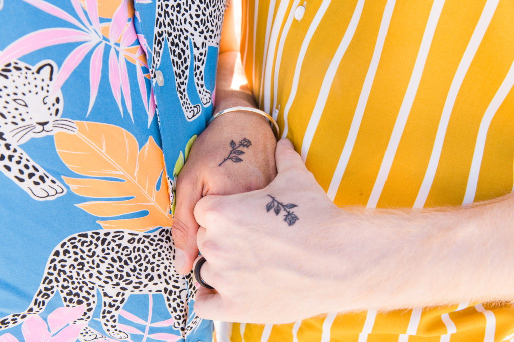 Two gay men with matching rose tattoo's on the top of their hands. 