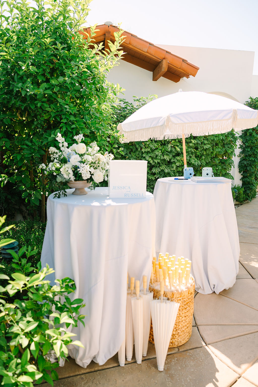 Details of an alcazar palm springs wedding ceremony welcome table with parasols and polaroid cameras