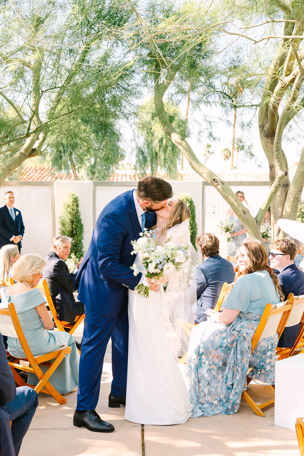 Newlyweds kiss in the aisle while exiting their outdoor alcazar palm springs wedding ceremony