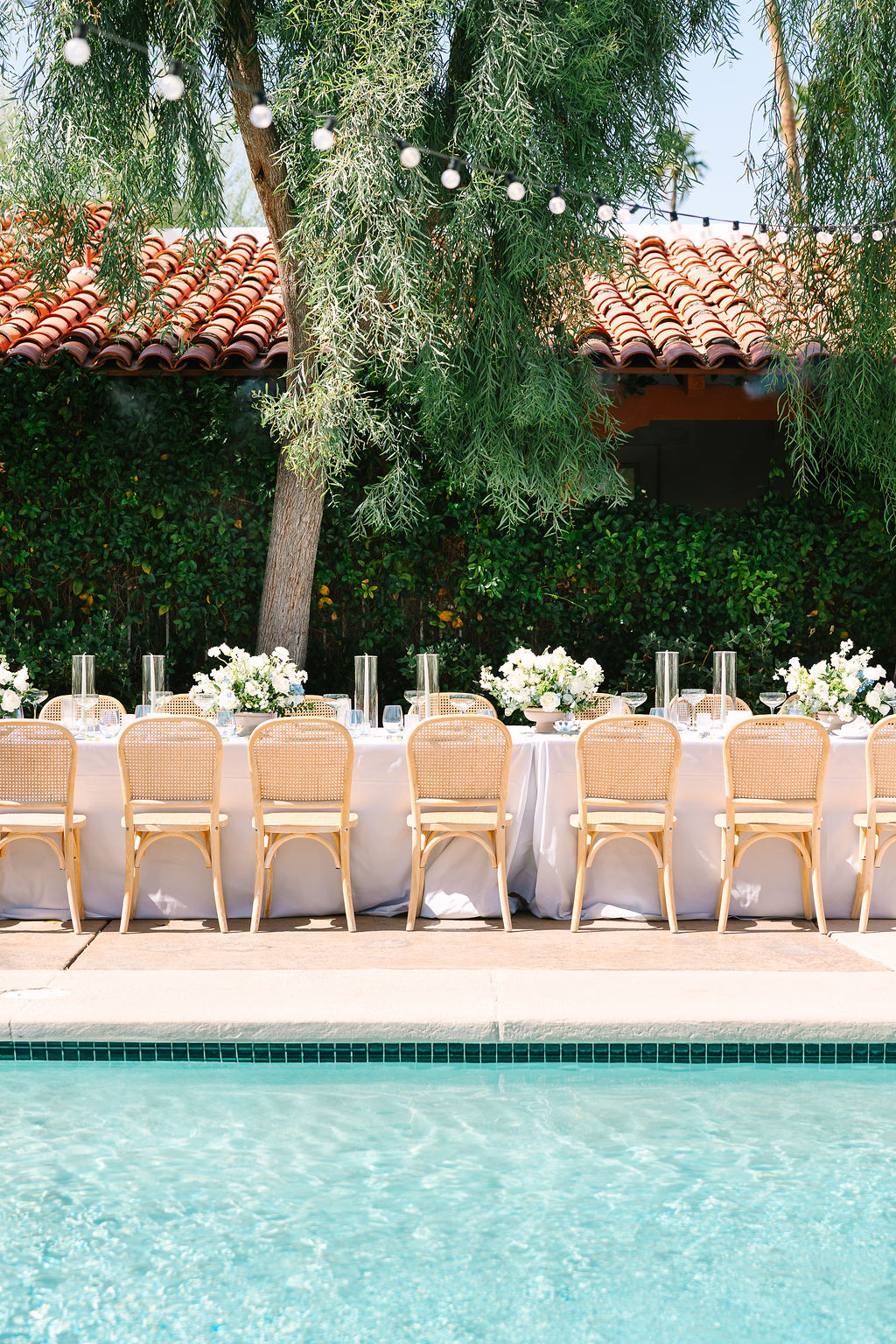 Details of a poolside wedding reception table set up with white florals