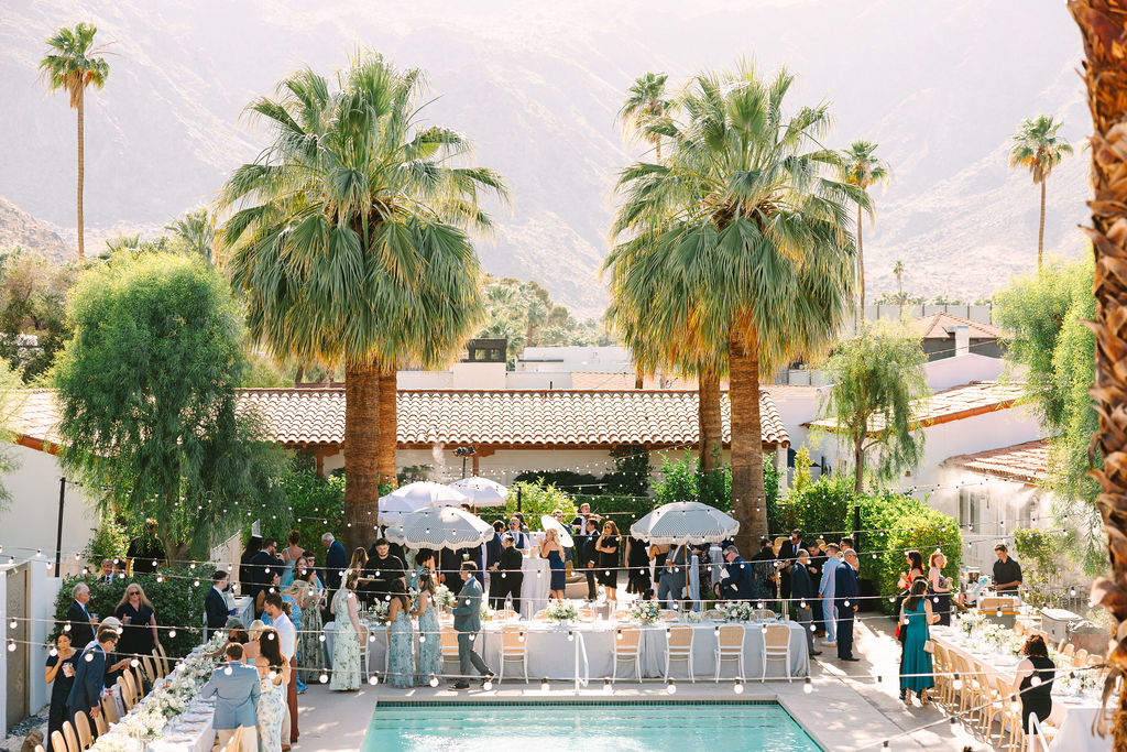 A look down at an active poolside wedding reception under market lights and palm trees