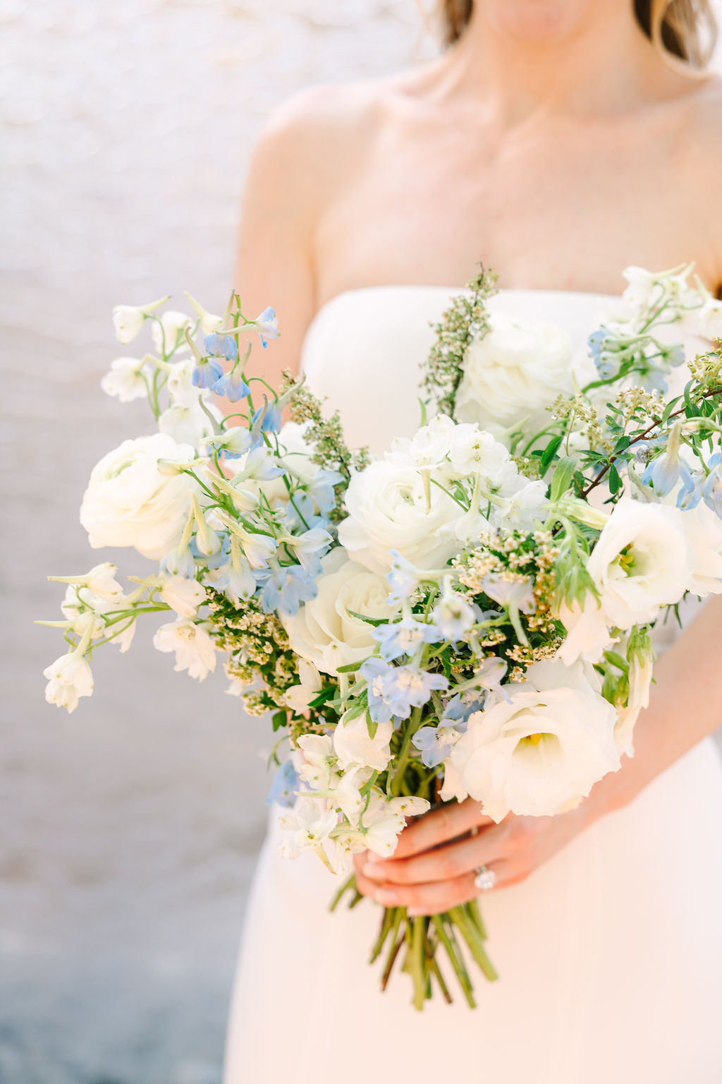 Details of a bride's white and blue bouquet as she holds it