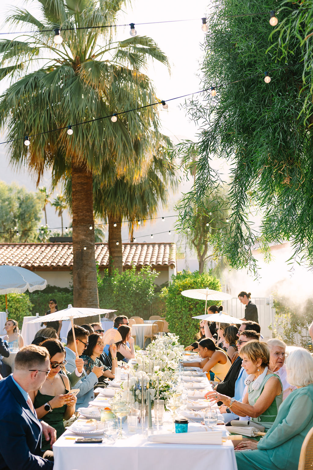 A peek down a long reception table at an active alcazar palm springs wedding reception