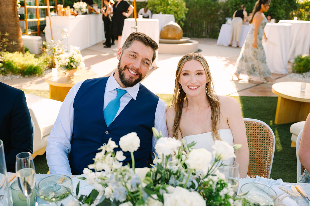 Happy newlyweds sit together during their outdoor wedding reception