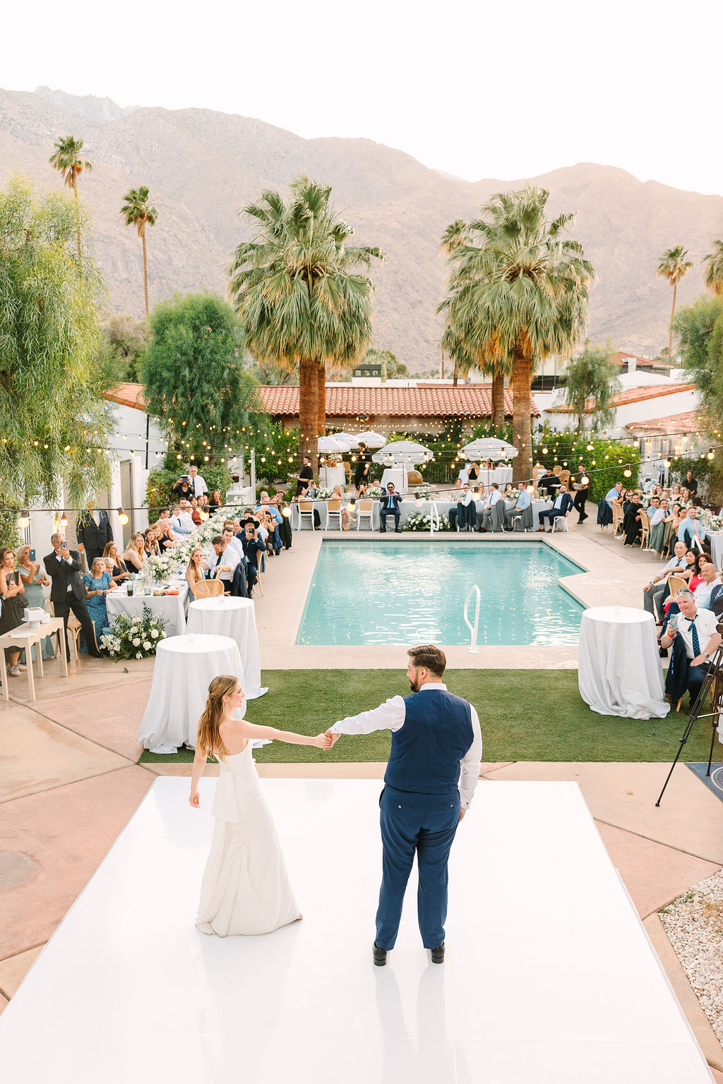 Newlyweds dance for the first time alone on the outdoor dance floor as guests sit and watch at their alcazar palm springs wedding