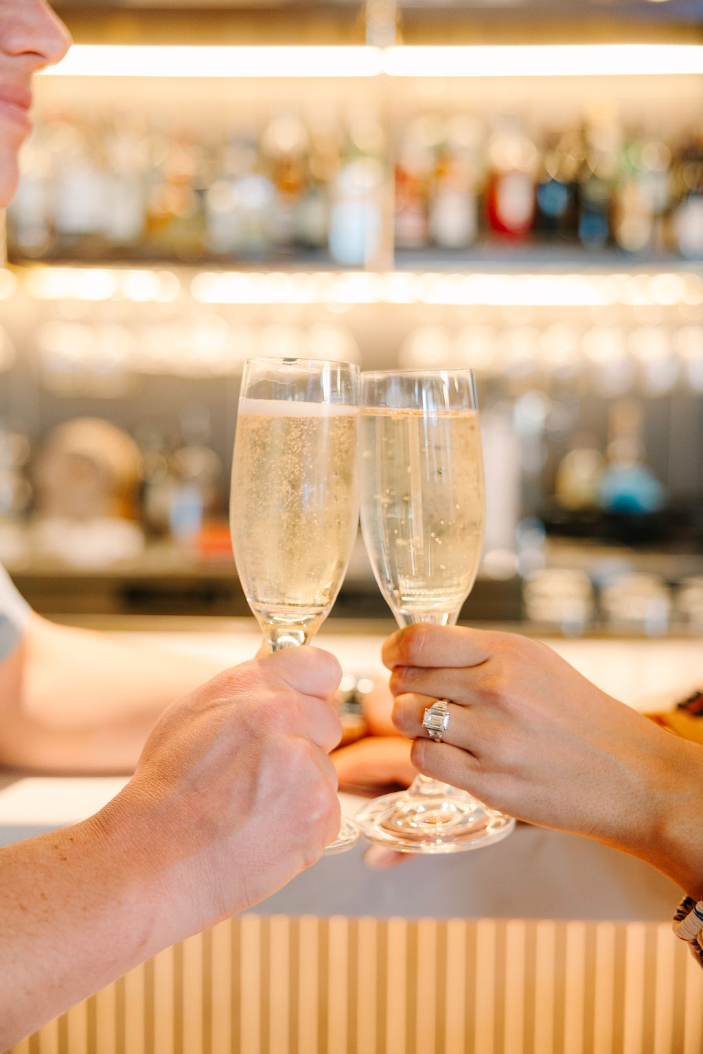 A couple toasts champagne while sitting at a bar