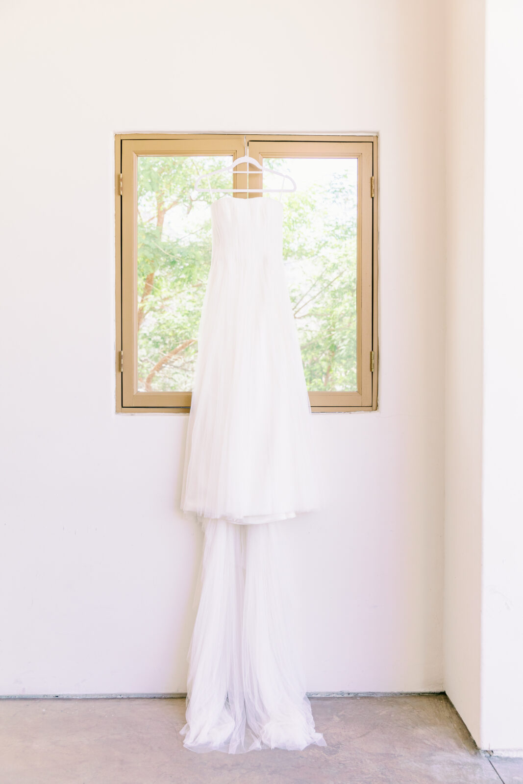 Details of a bride's dress hanging in a window