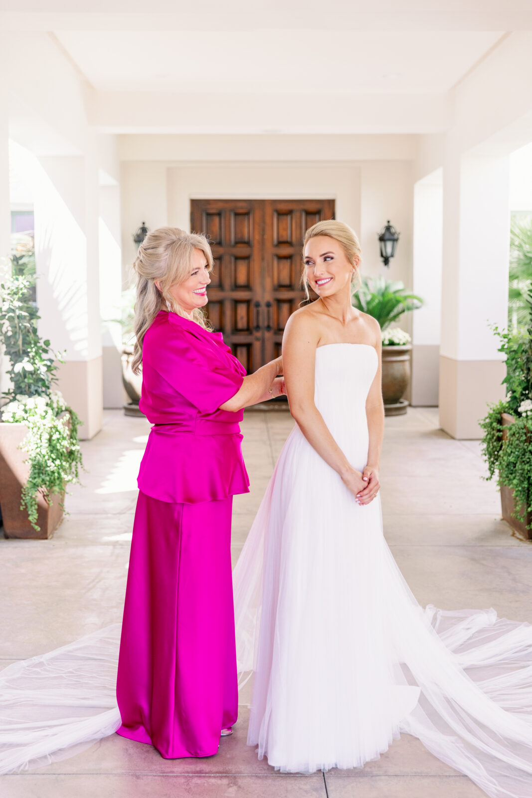 Mom helps her daughter button up her wedding gown as they smile at each other at her la quinta country club wedding