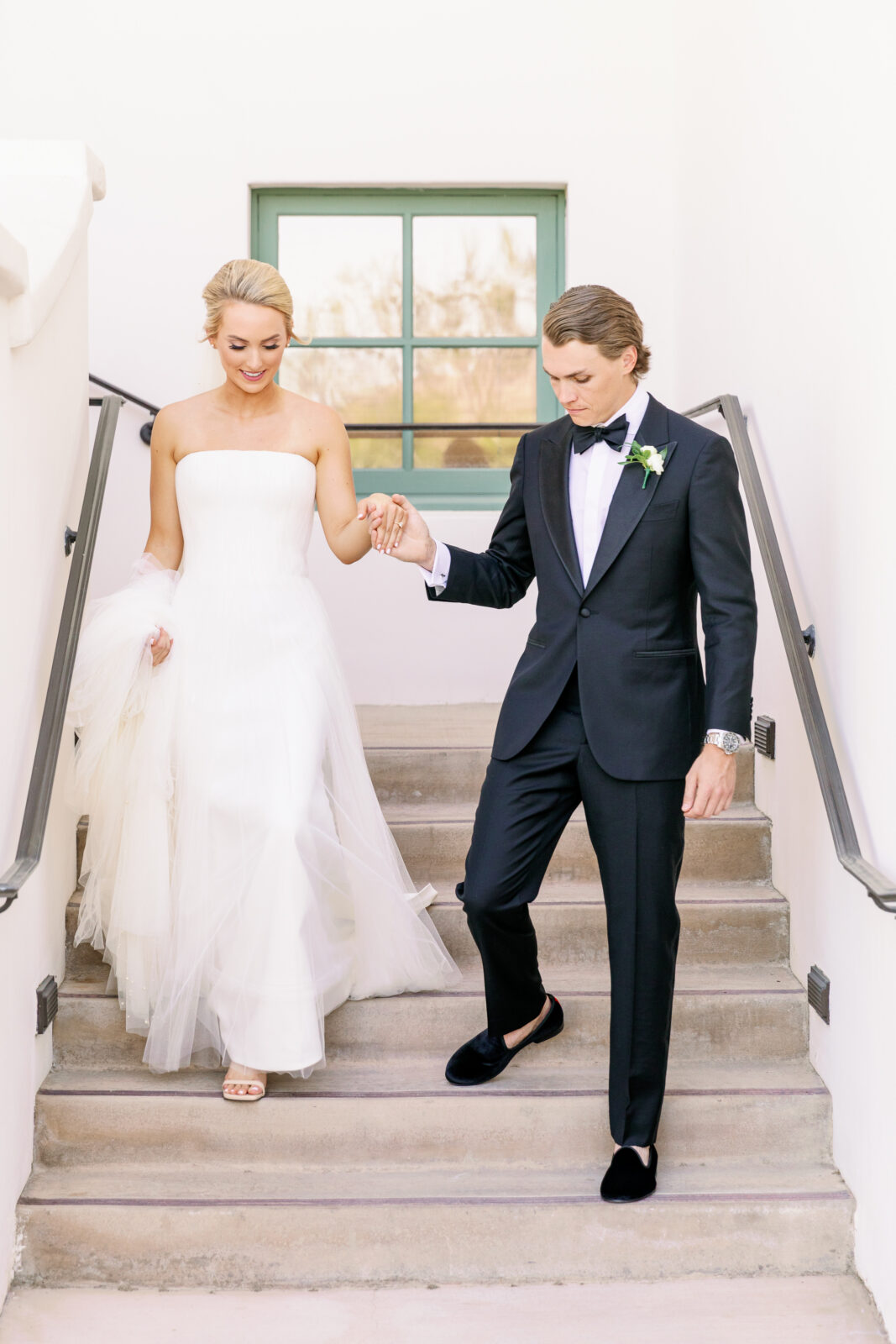 A bride and groom walk down the stairs holding hands and the train at la quinta country club wedding