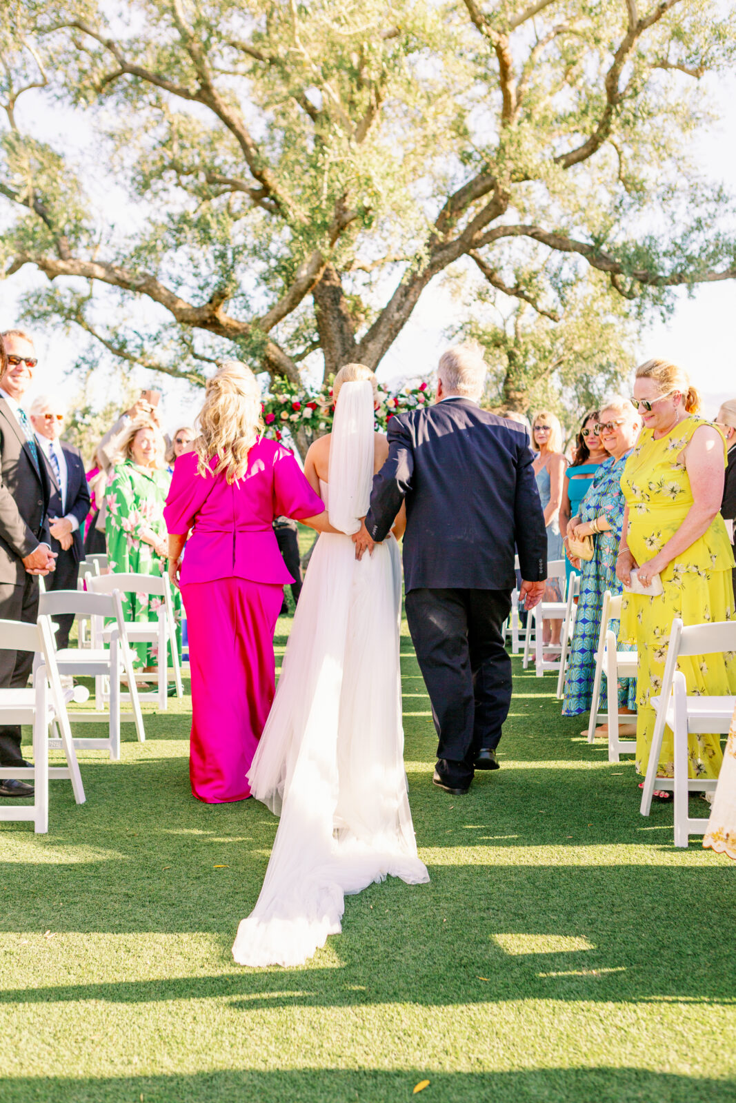 Mom and dad walk their daughter down the aisle for her outdoor ceremony