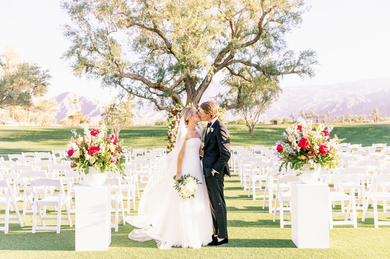 A bride and groom kiss in the aisle of their empty la quinta country club wedding ceremony