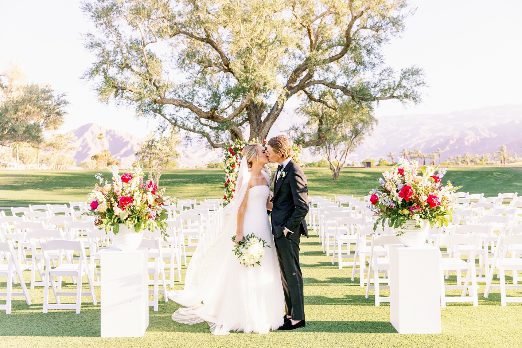 A bride and groom kiss in the aisle of their empty la quinta country club wedding ceremony