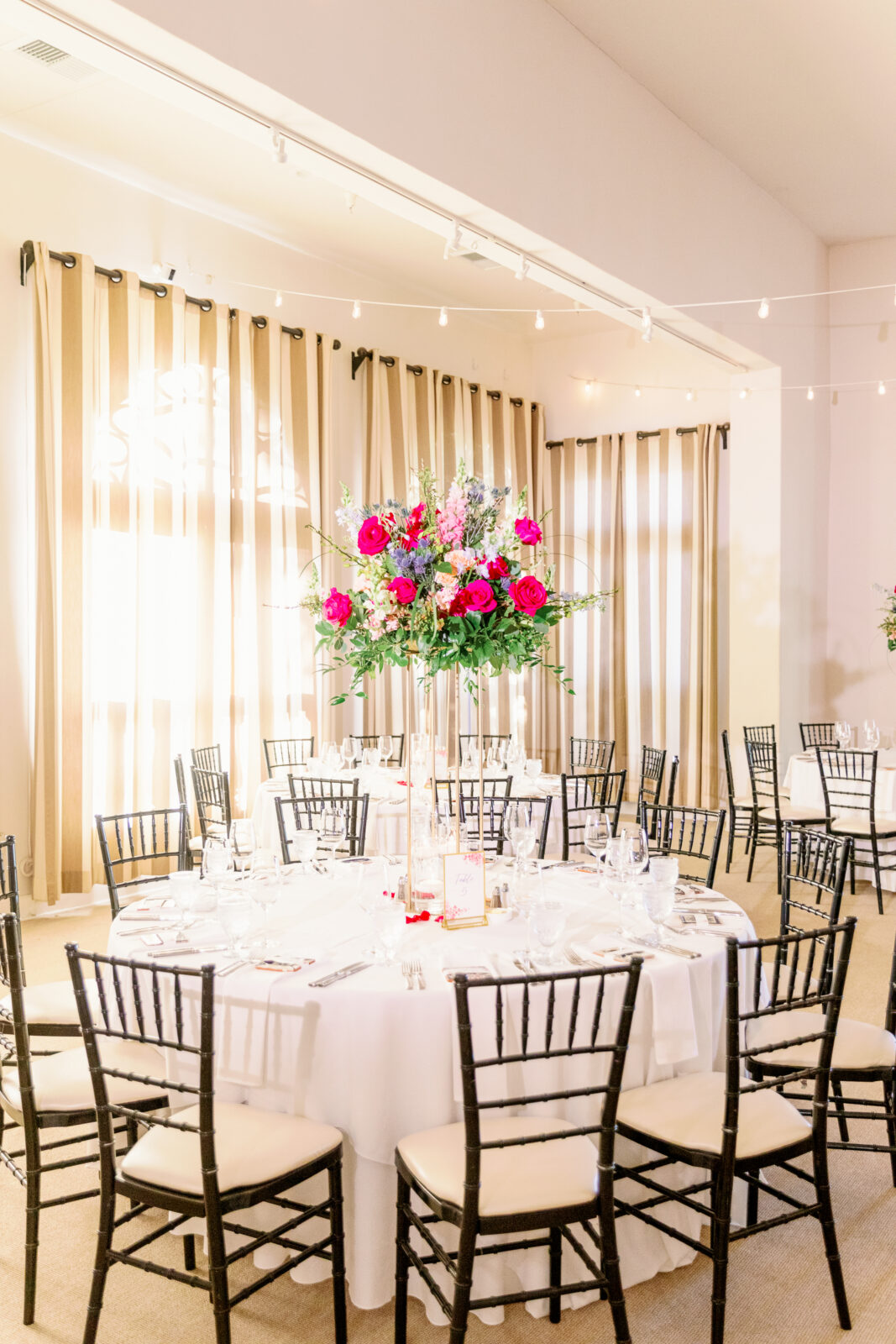 Details of a round reception table with white linen and black chairs