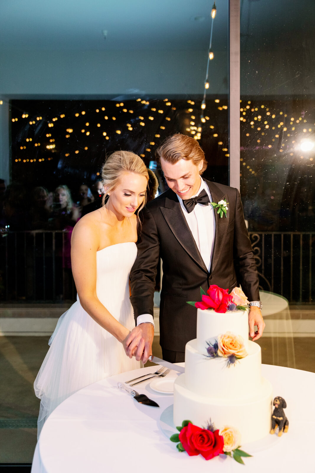 Newlyweds cut the cake in a large window