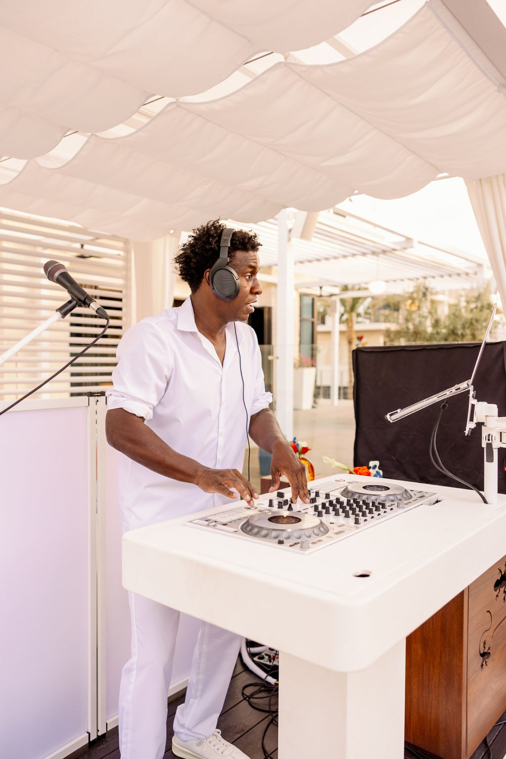 A DJ in white stands at his turntable with headphones on