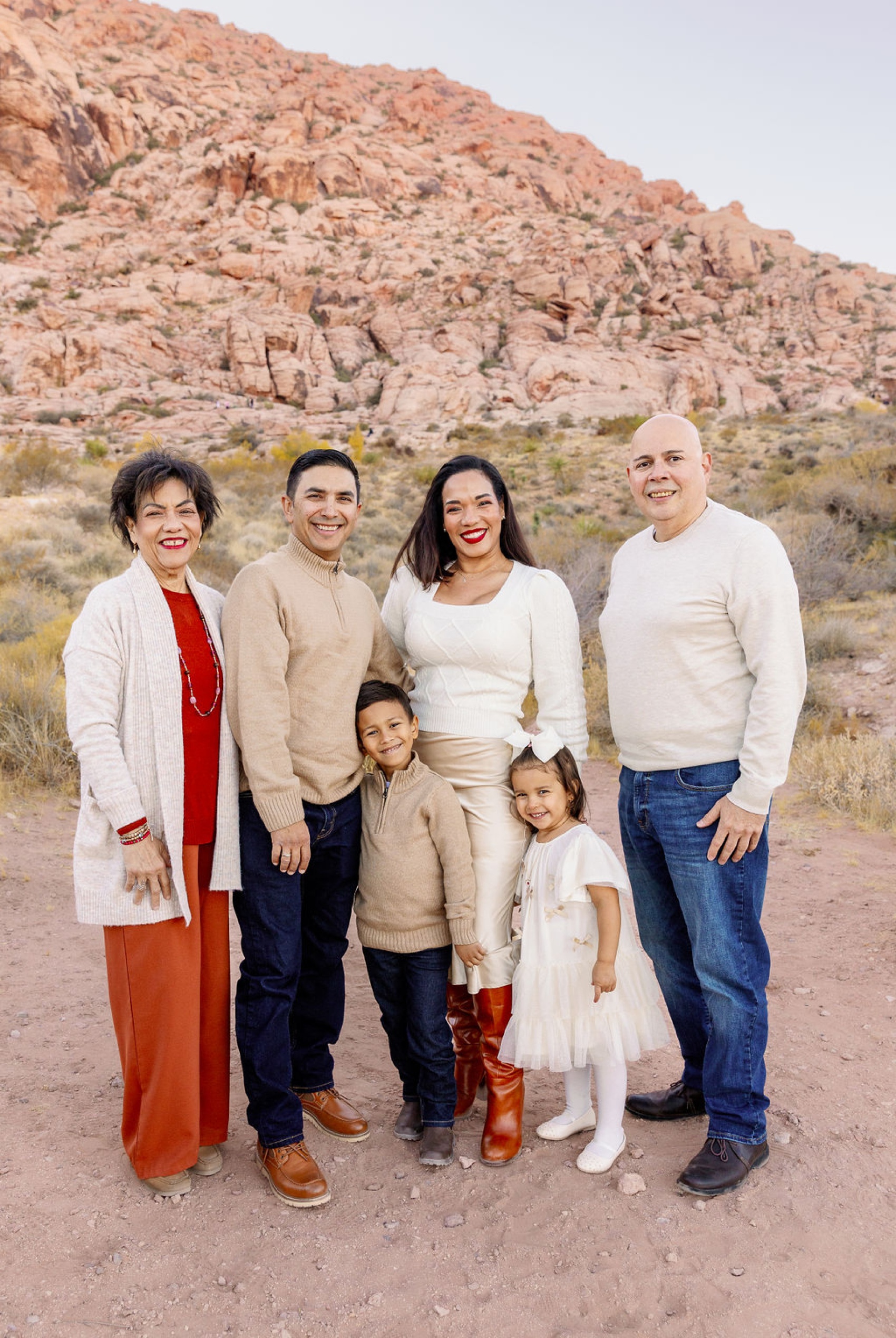 A happy family stand smiling with grandma and grandpa in red rocks with arms around each other