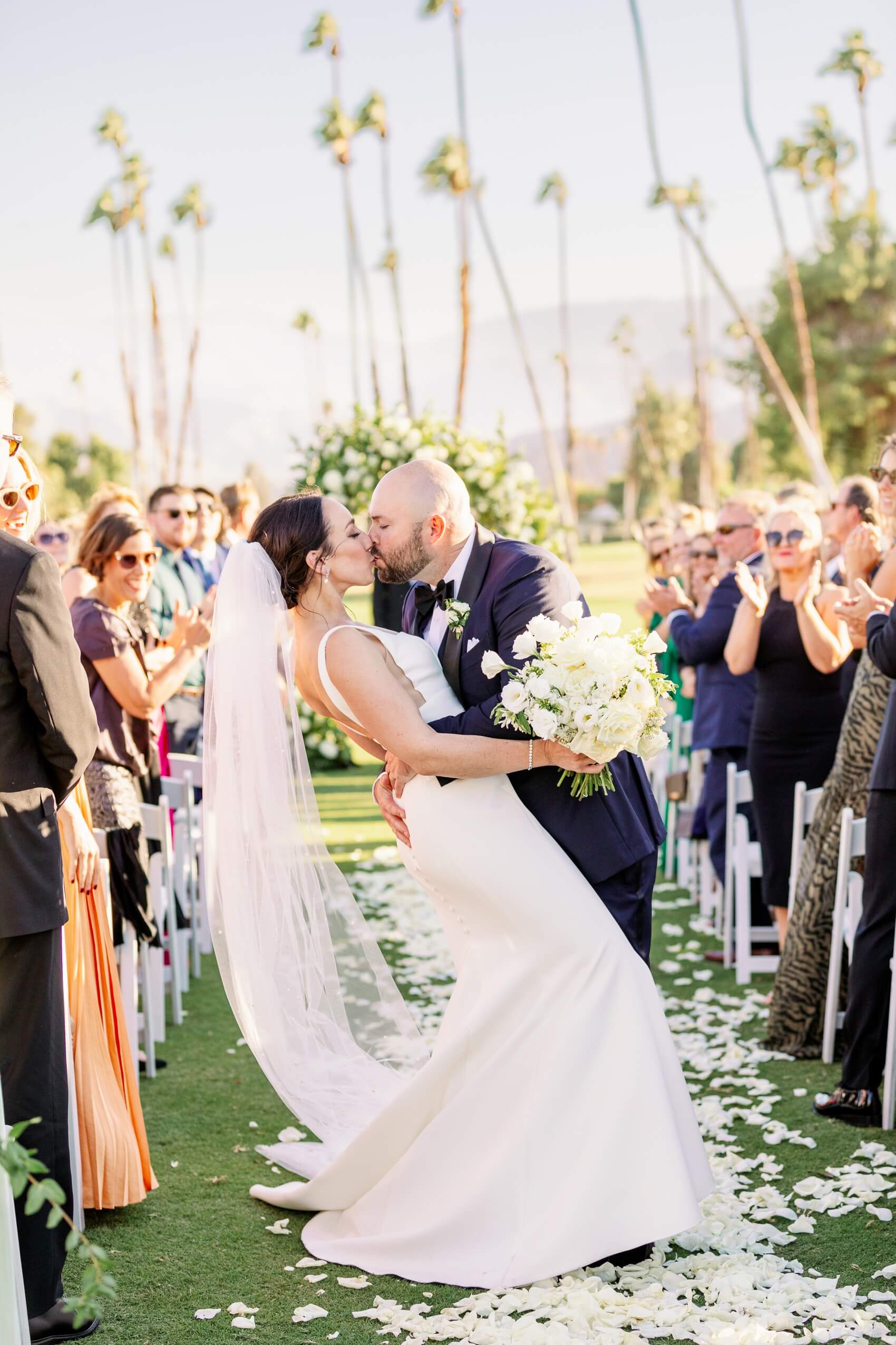 A groom dips and kisses his bride in the ceremony aisle to end their rancho las palmas wedding ceremony