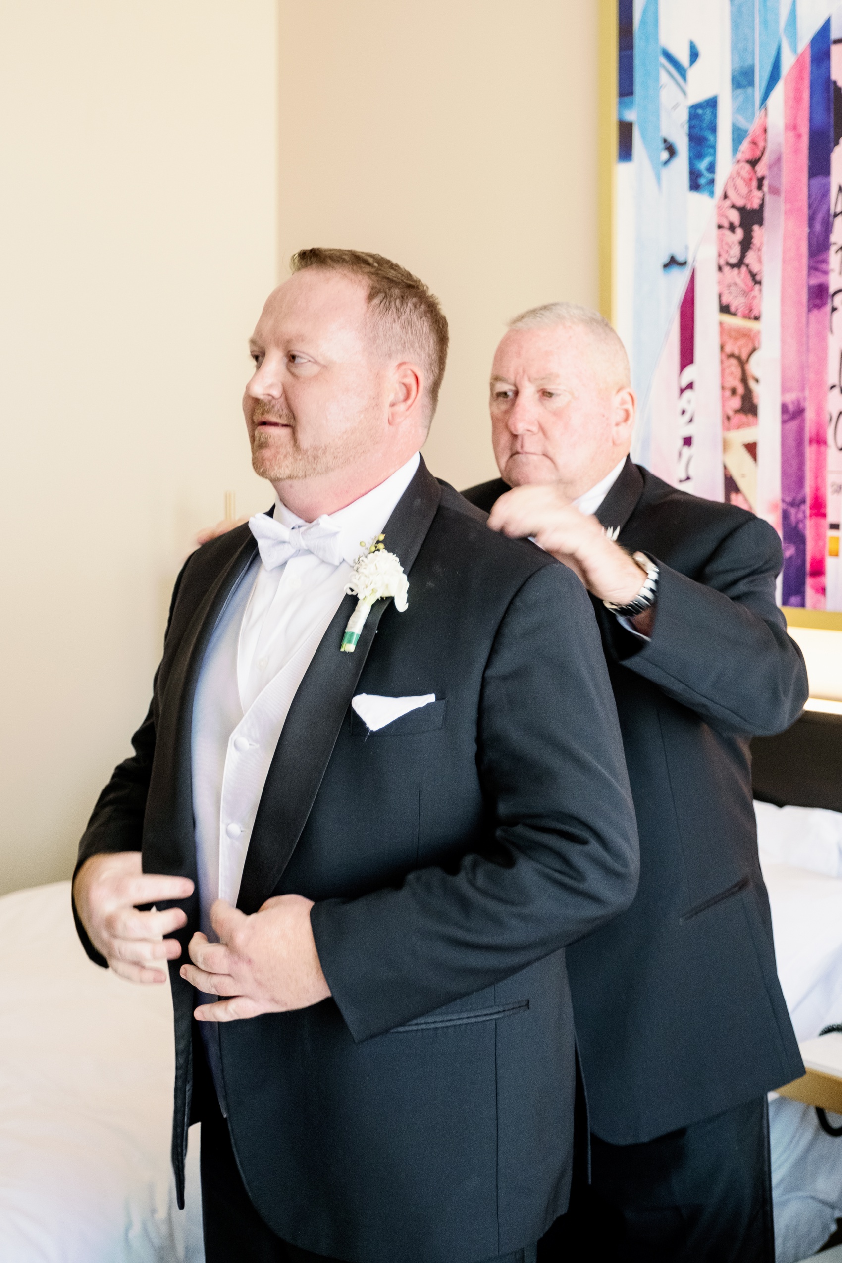A groom gets ready with help from dad in a hotel suite