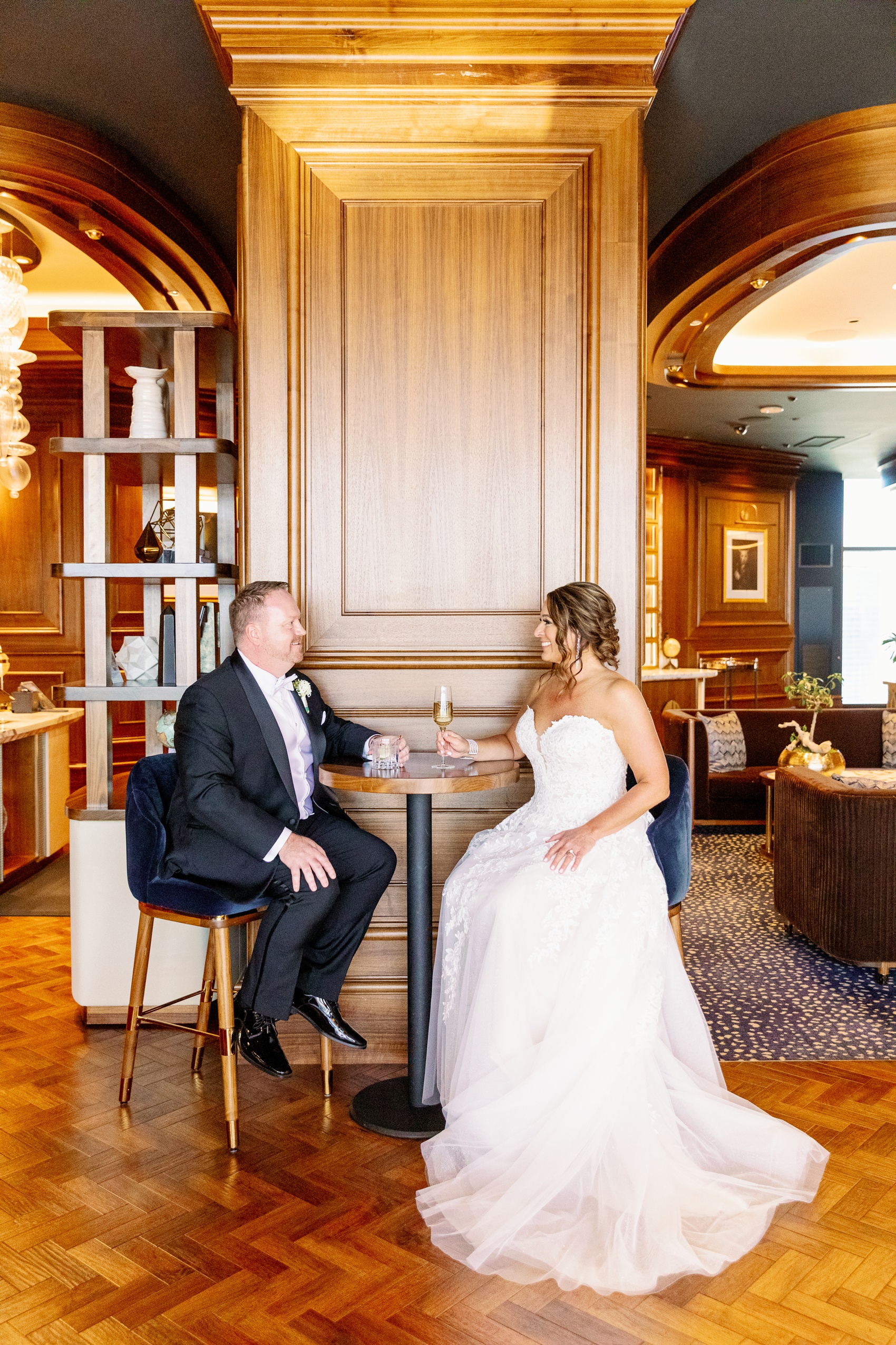 A bride smiles with champagne while sitting with her happy groom sitting in a luxurious vegas bar
