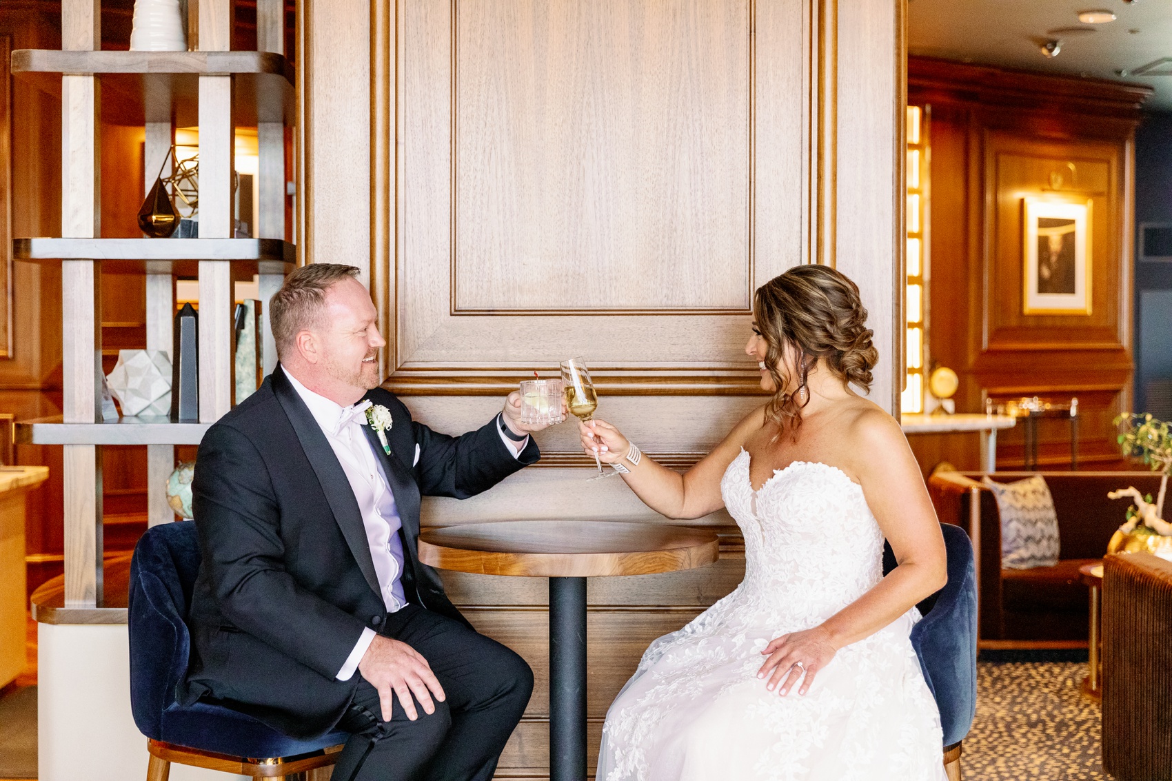 newlyweds toast while sitting at the resorts world wedding venue bar high top table