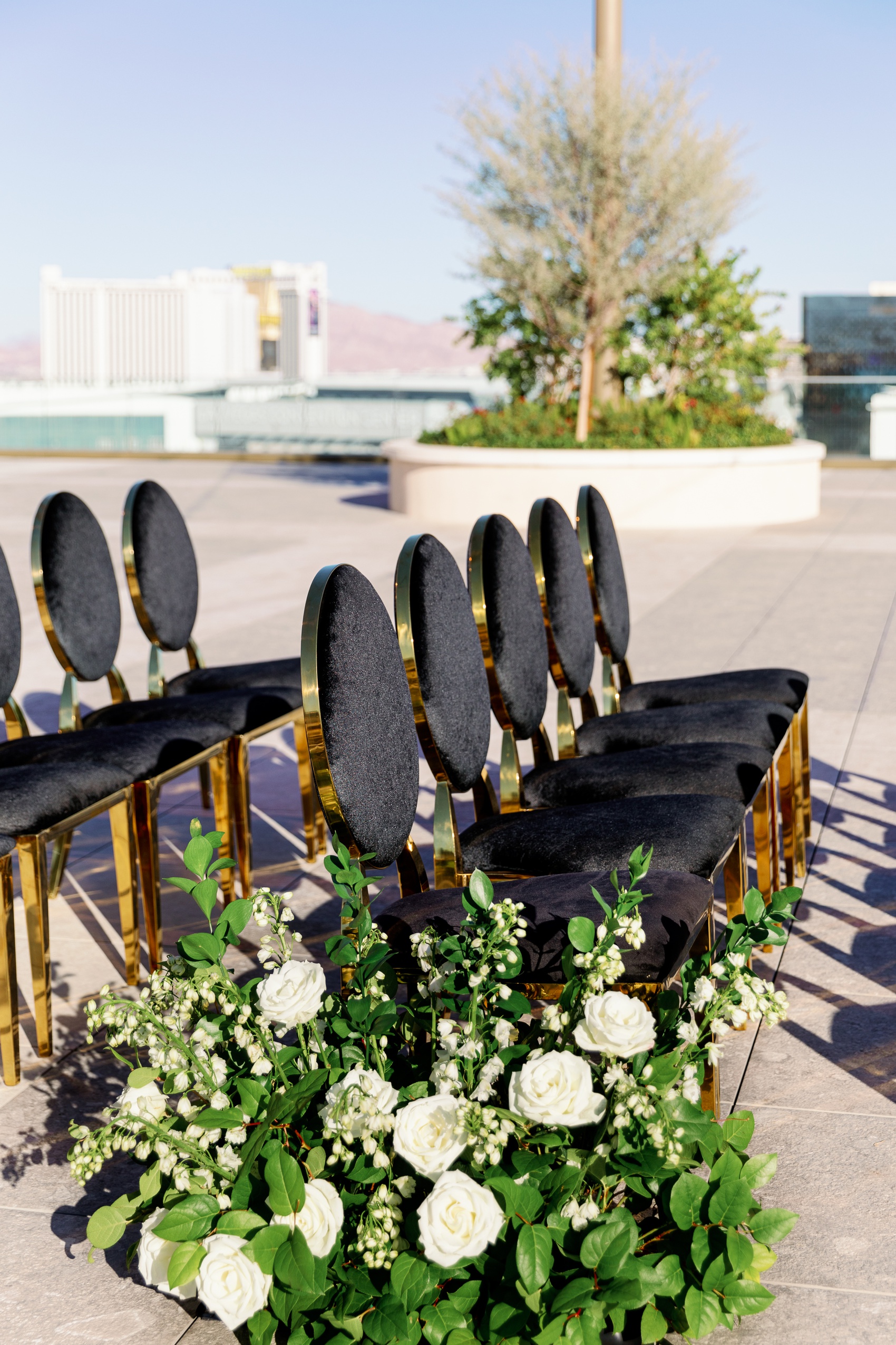 Details of black and gold wedding ceremony chairs with white roses on a rooftop