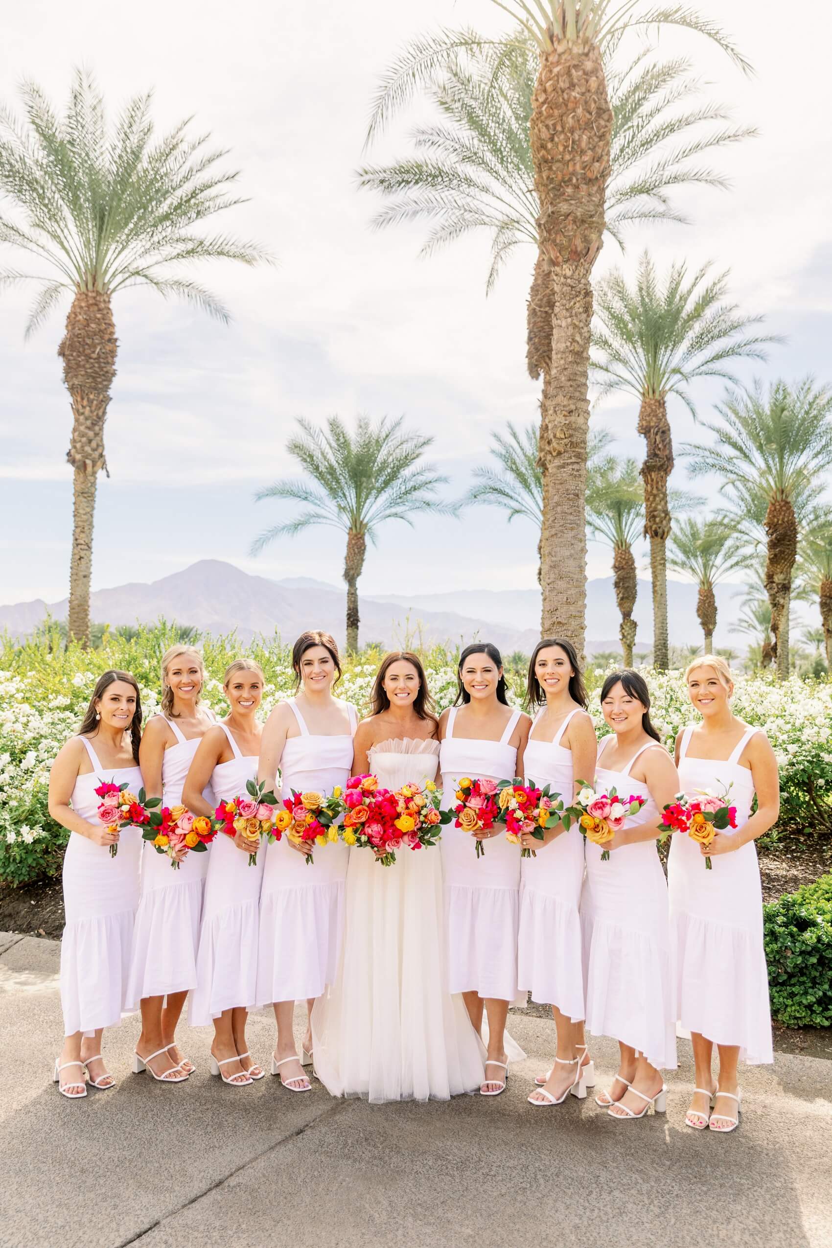 A bride stands with her bridesmaids in white gowns in the toscana country club wedding venue