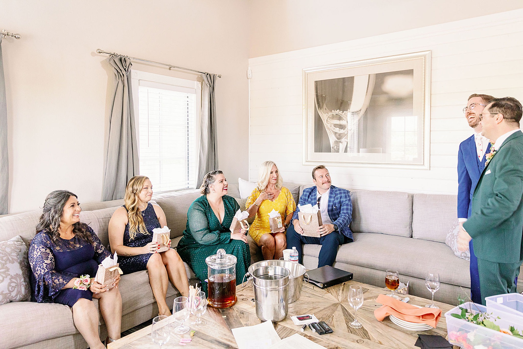 Groom laugh with family and guests in the getting ready suite