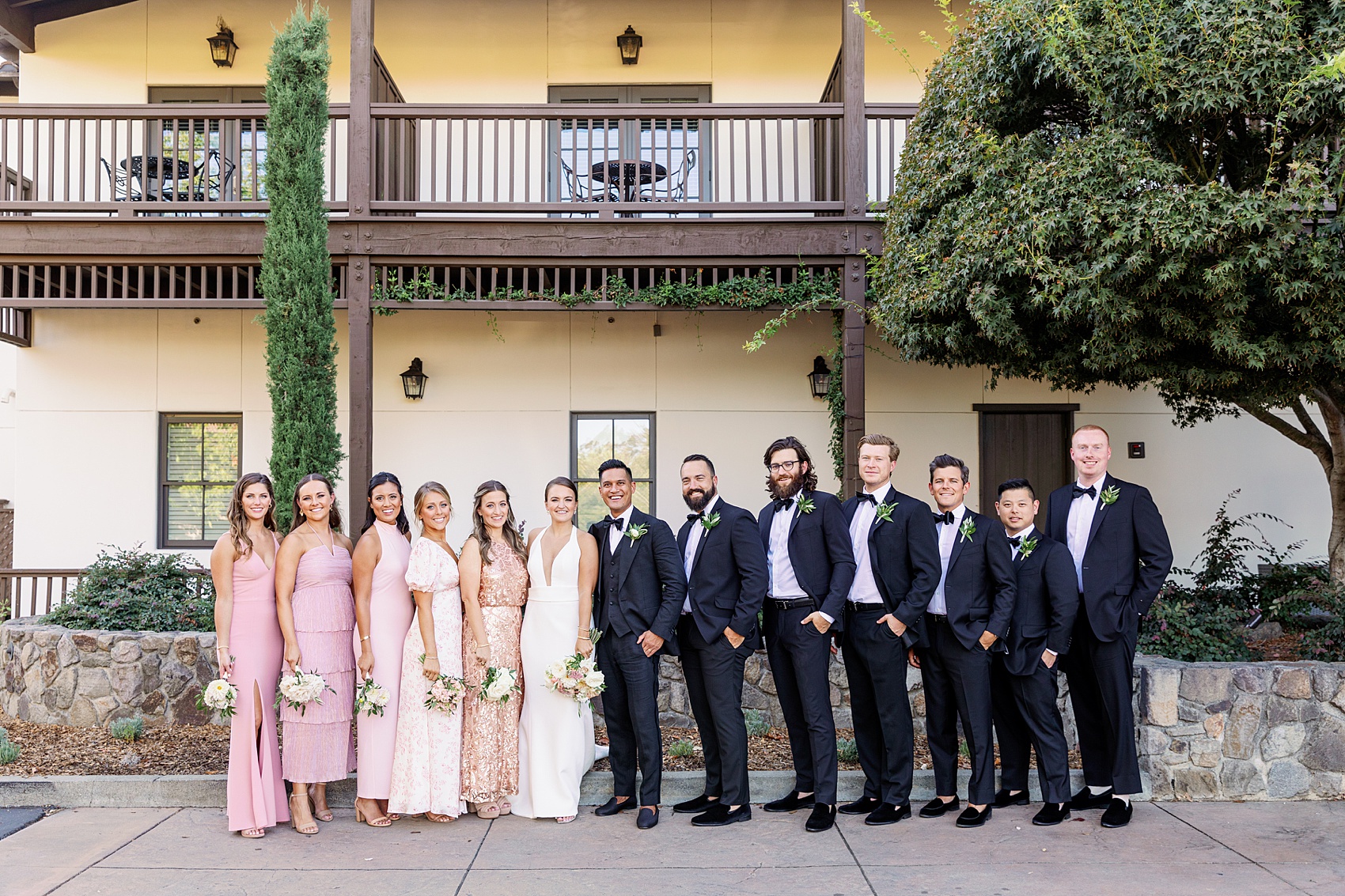 Newlyweds stand with their wedding party in a sidewalk