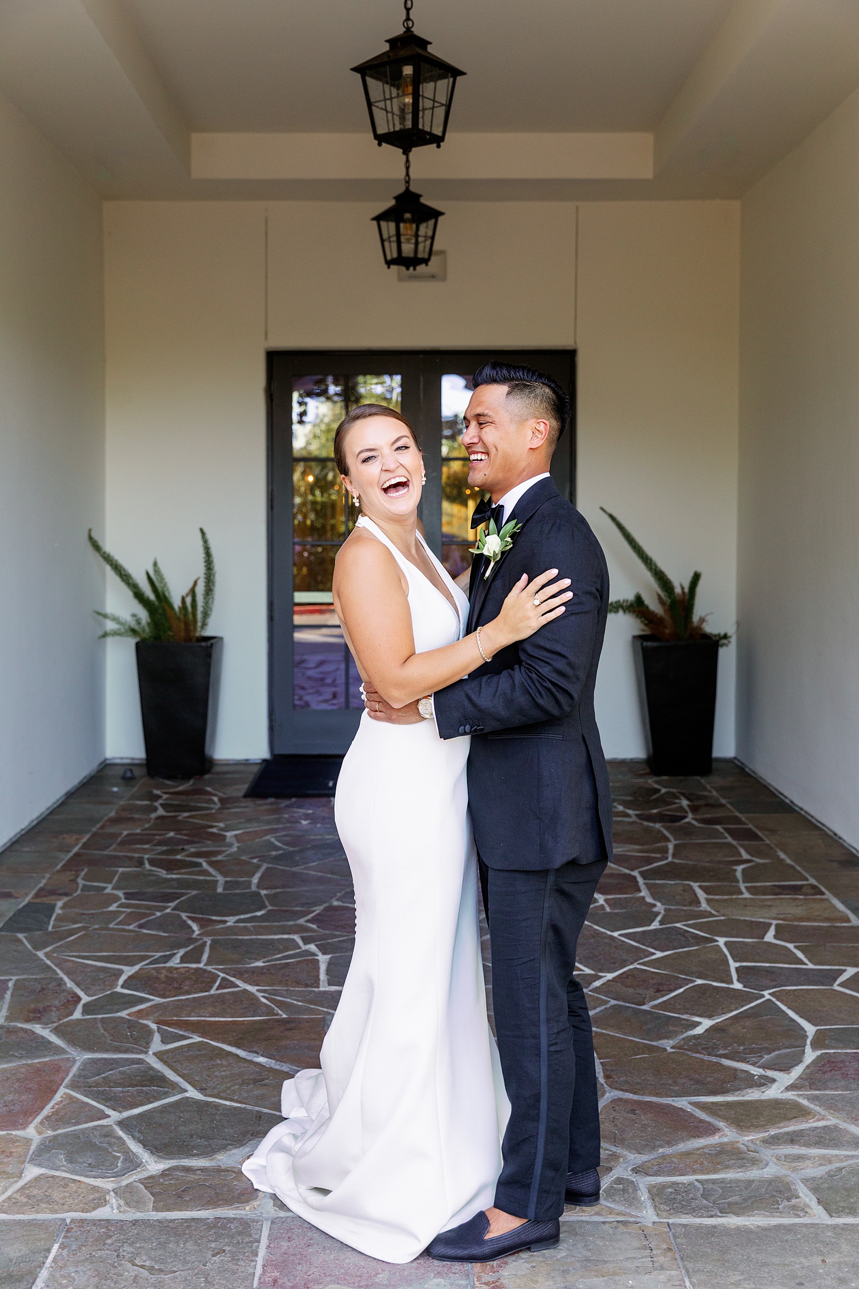 Newlyweds laugh big while hugging in a hallway at the lodge at sonoma wedding venue