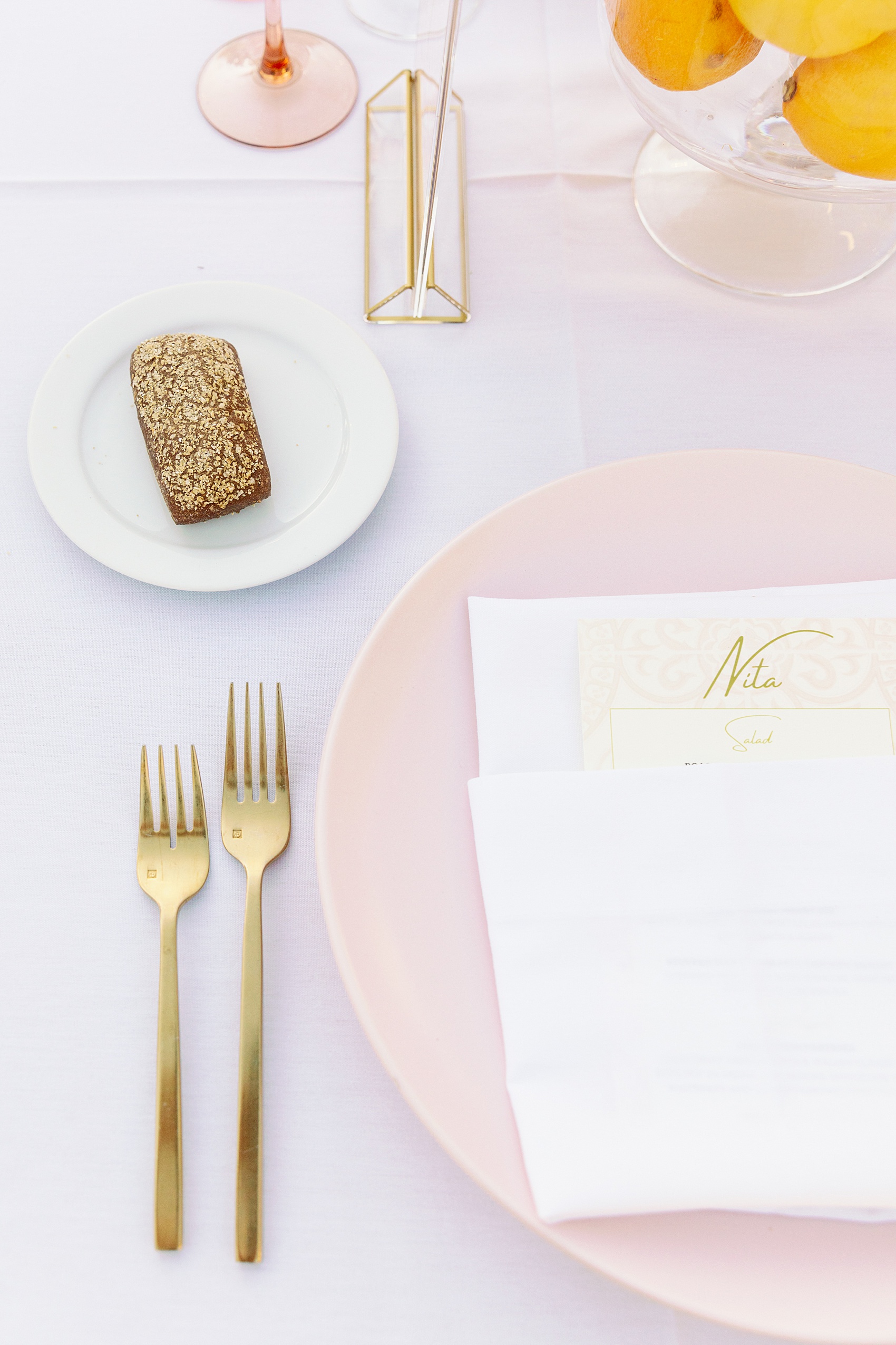 Details of a wedding placement with hold silverware and pink plates