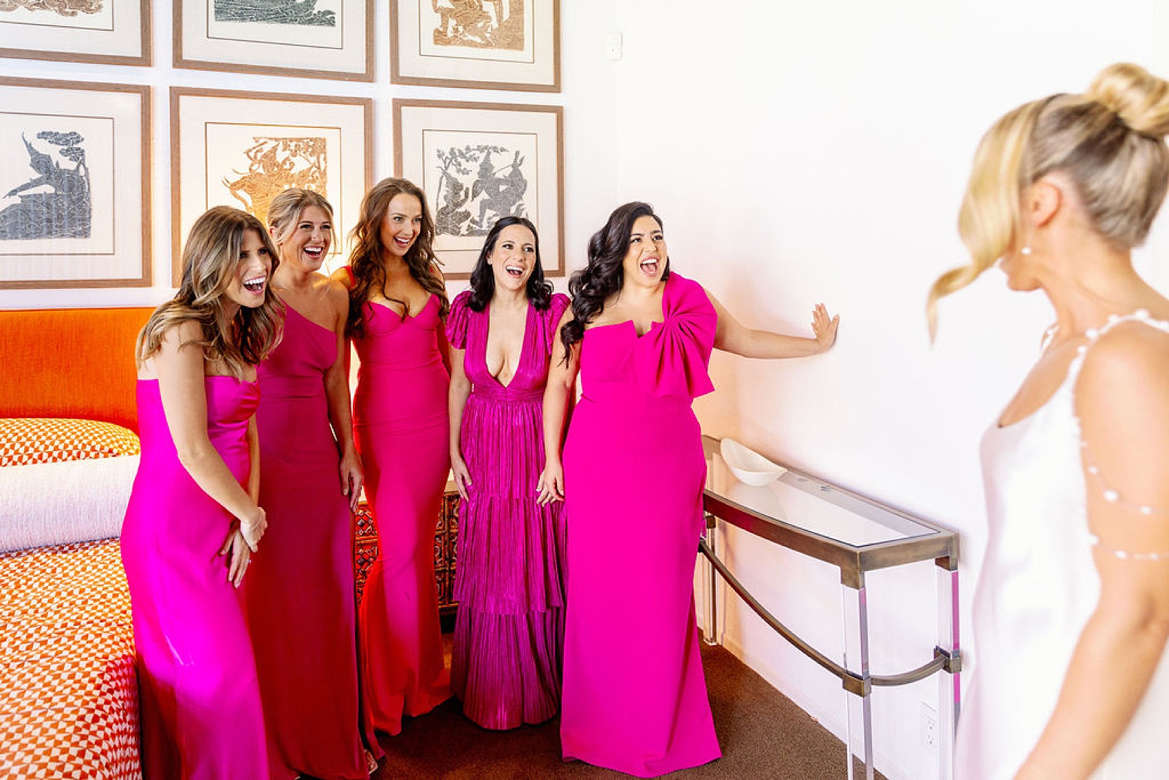 Bridesmaids in hot pink celebrate seeing the bride in her gown