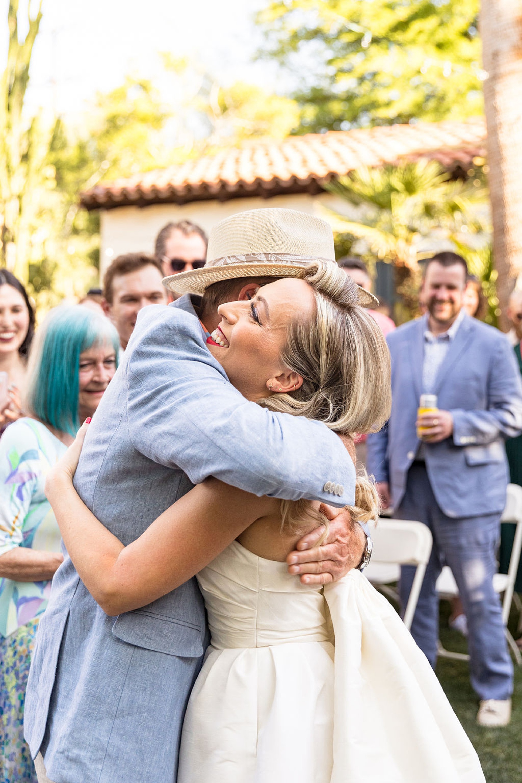 A bride hugs her father in a blue suit after coming down the aisle