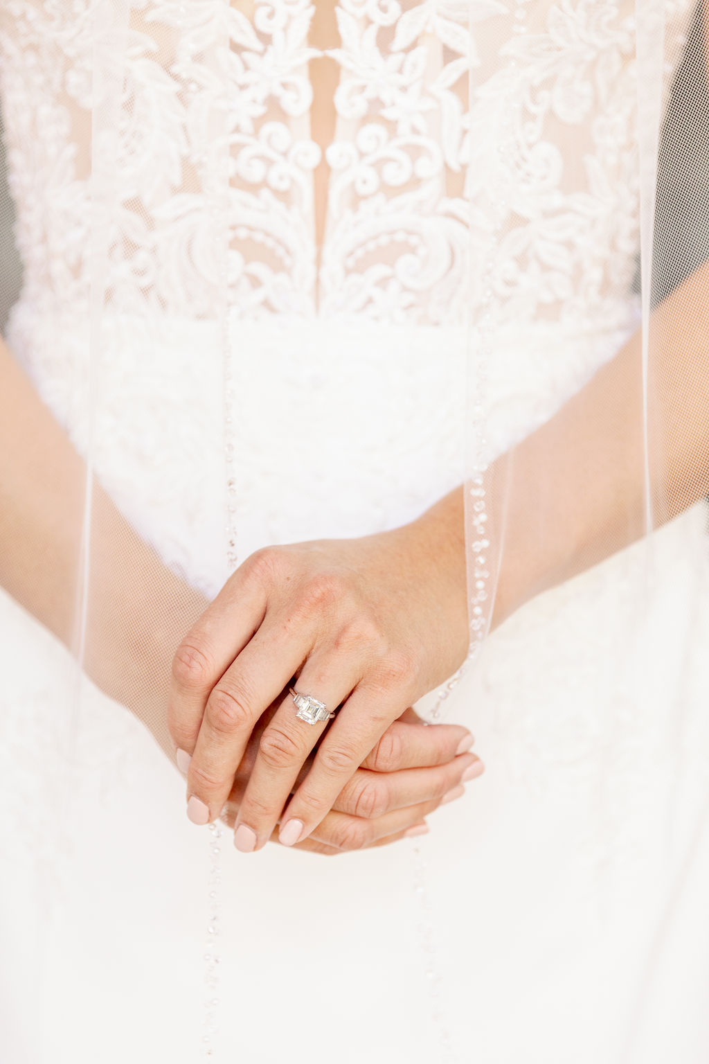 Details of a bride's hands with engagement ring and long veil