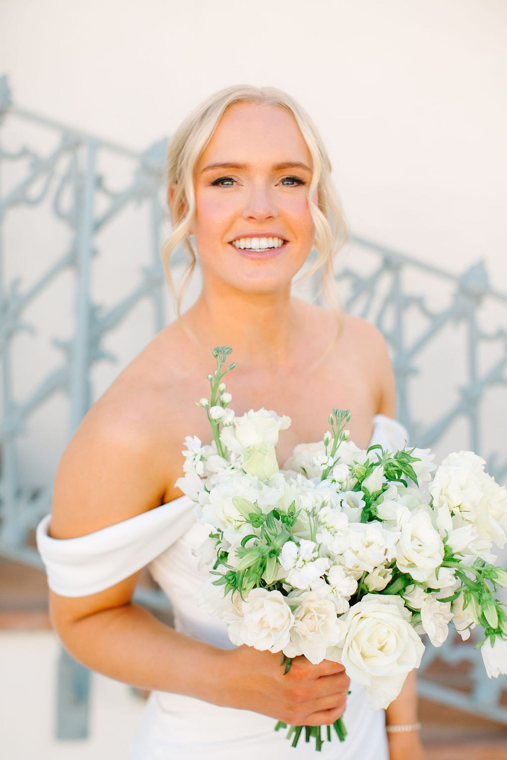 A happy bride smiles while holding her white rose bouquet at her merv griffin estate wedding